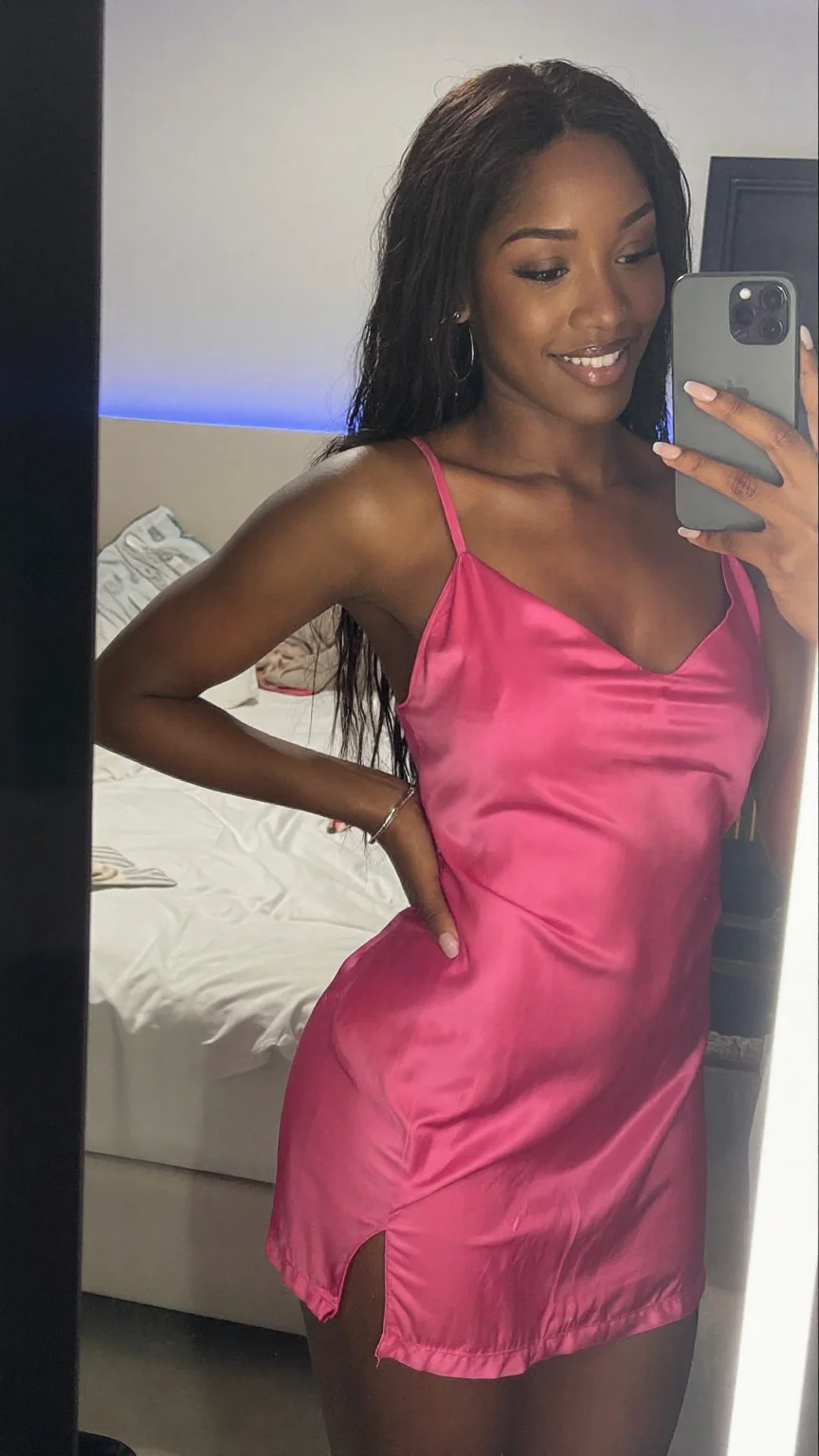 Woman in pink satin taking a confident mirror selfie